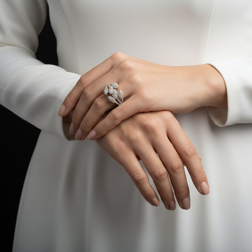 Pair of silver earrings with clear stones on a gray background, branded 'Saheli'.