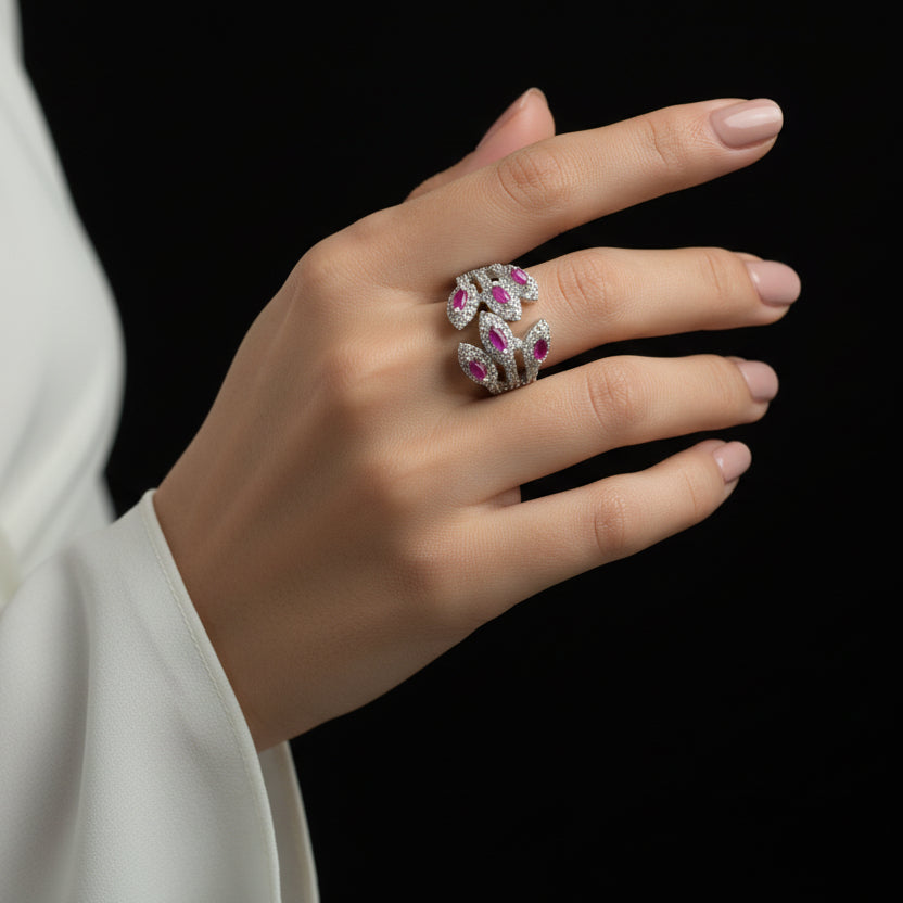 Silver ring with pink gemstones on a gray background, featuring the brand 'Saheli'.