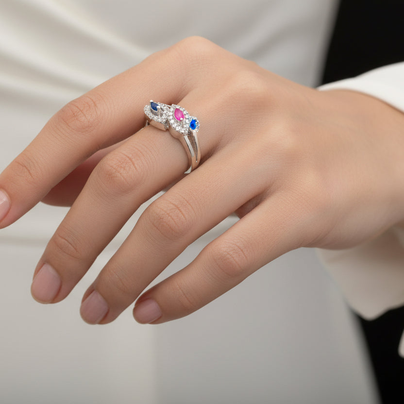 Silver ring with colored stones on a gray background, branded 'SAHELL'.