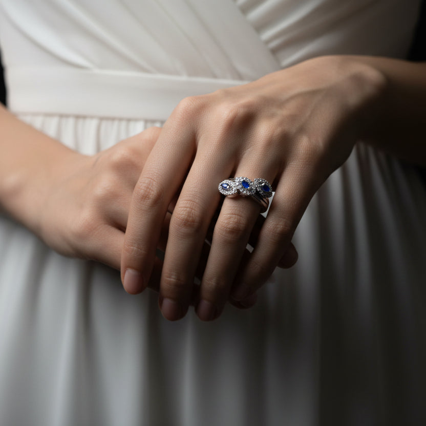 Silver ring with blue gemstones on a gray background, featuring the brand 'SAHELI'.