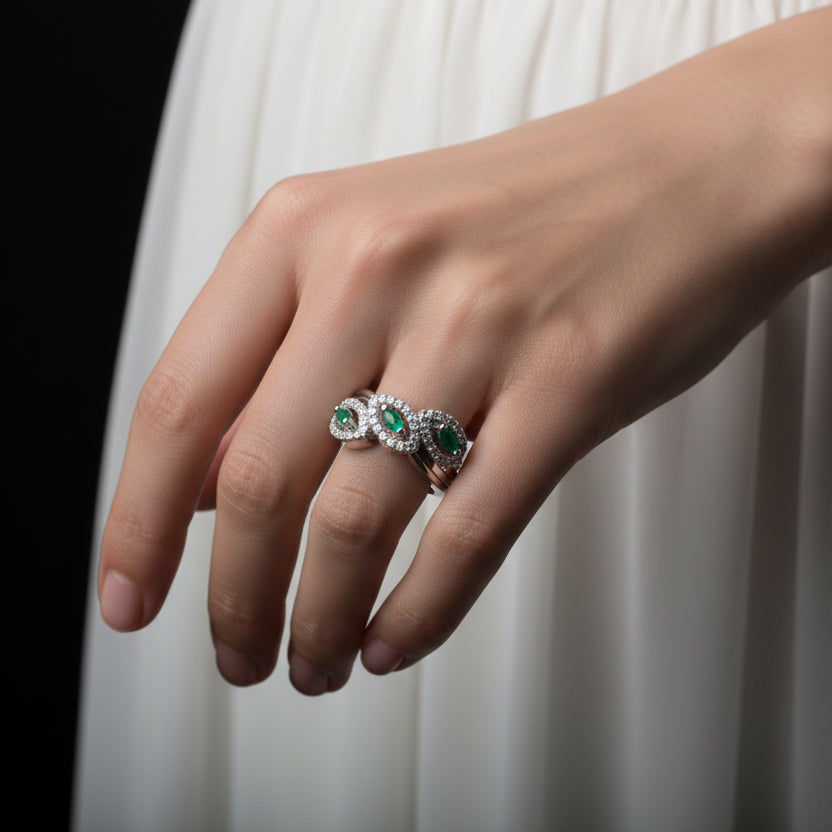 Silver ring with green gemstones on a gray background, featuring the brand 'SAHELI'.
