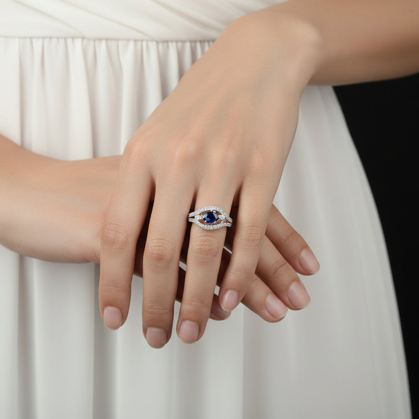 Silver ring with a blue gemstone on a black hand model, featuring the brand 'Saheli'.