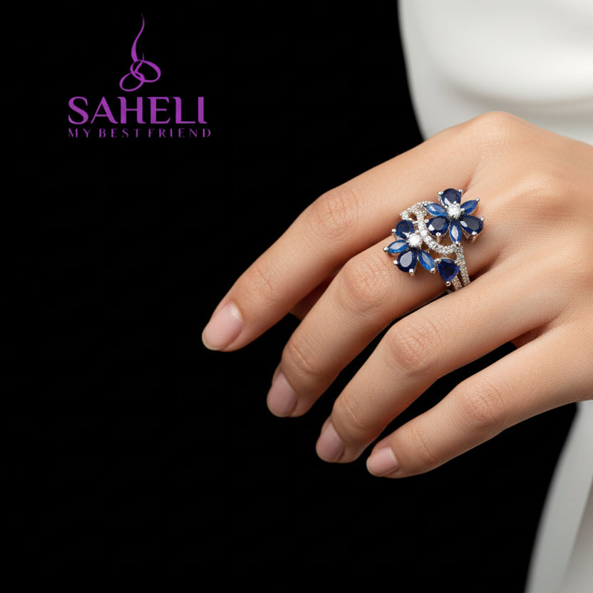 Silver ring with blue gemstones on a black background, featuring the brand 'Saheli'.