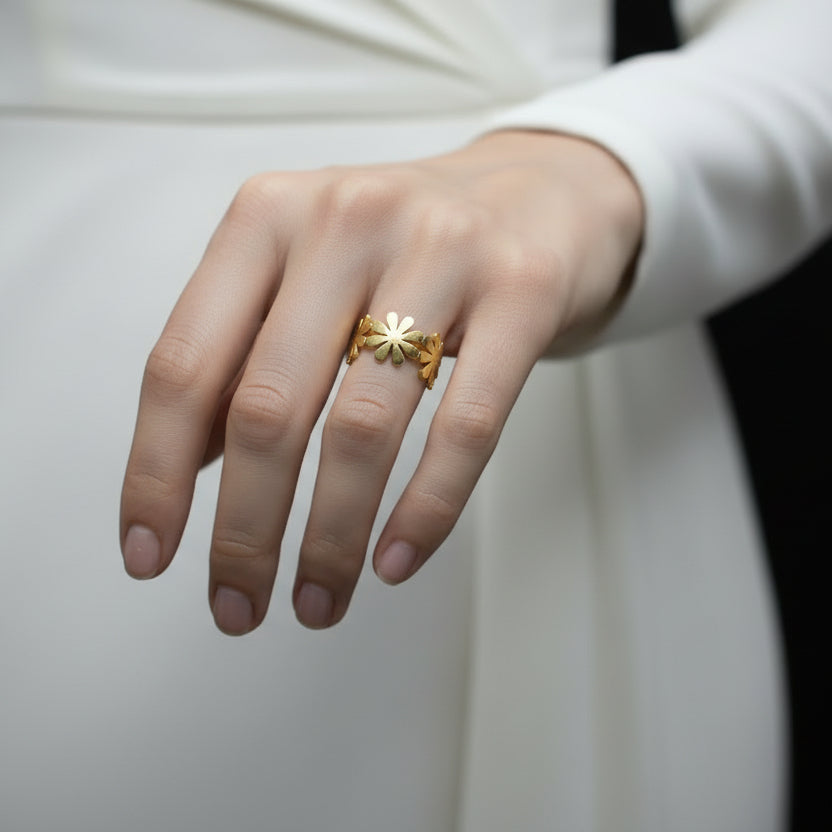 Gold floral earring on a black hand model