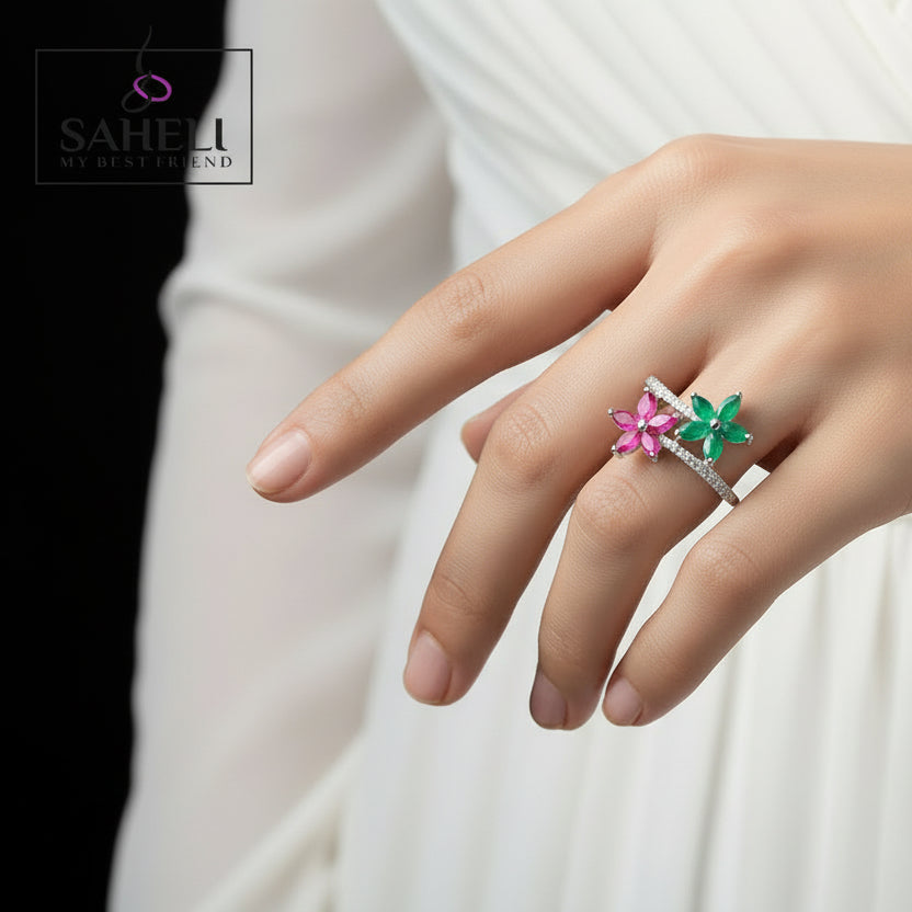 Flower-shaped earrings on a black hand model with 'Saheli' branding.