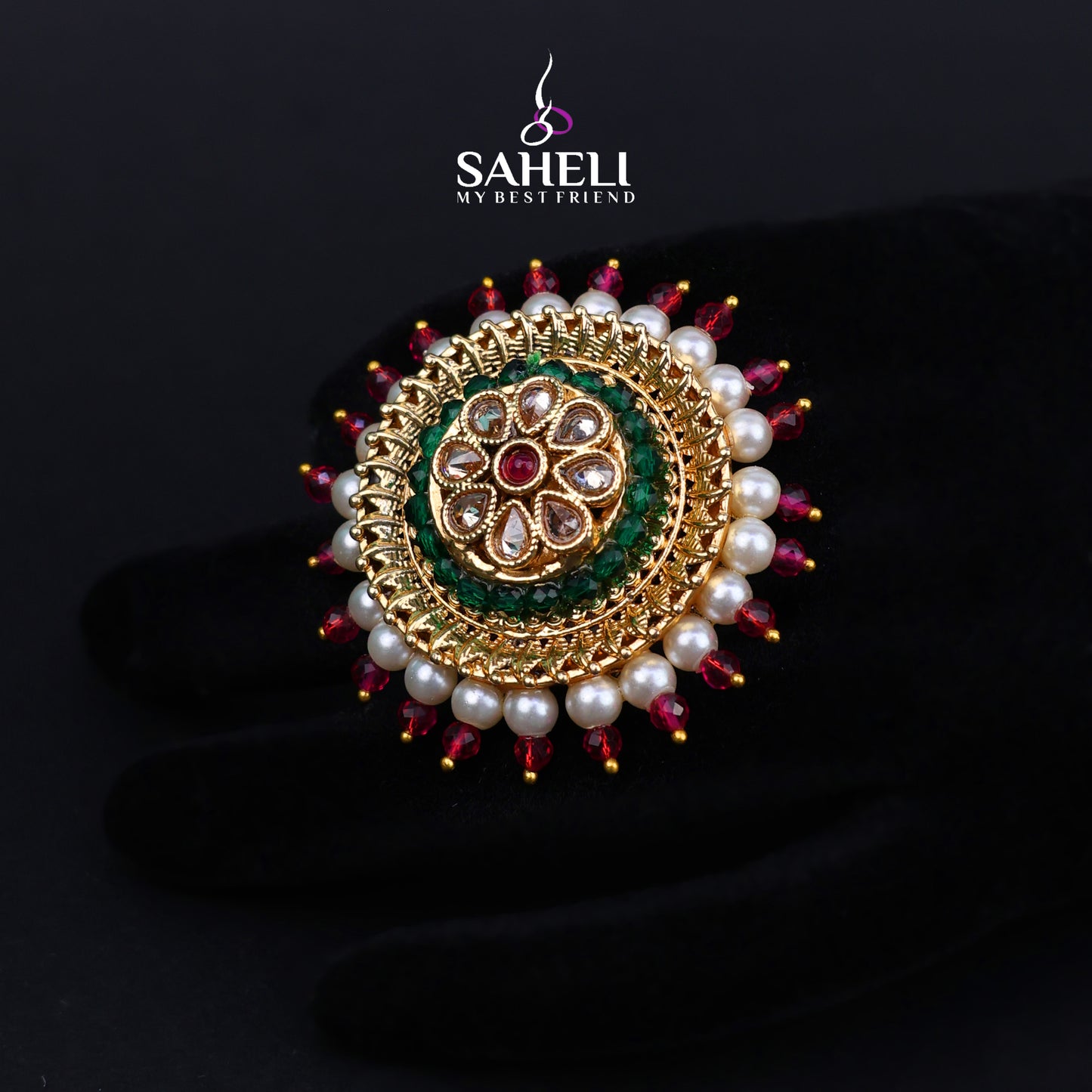 Jewelry item with pearls and gemstones on a dark background, featuring the brand 'Saheli'.