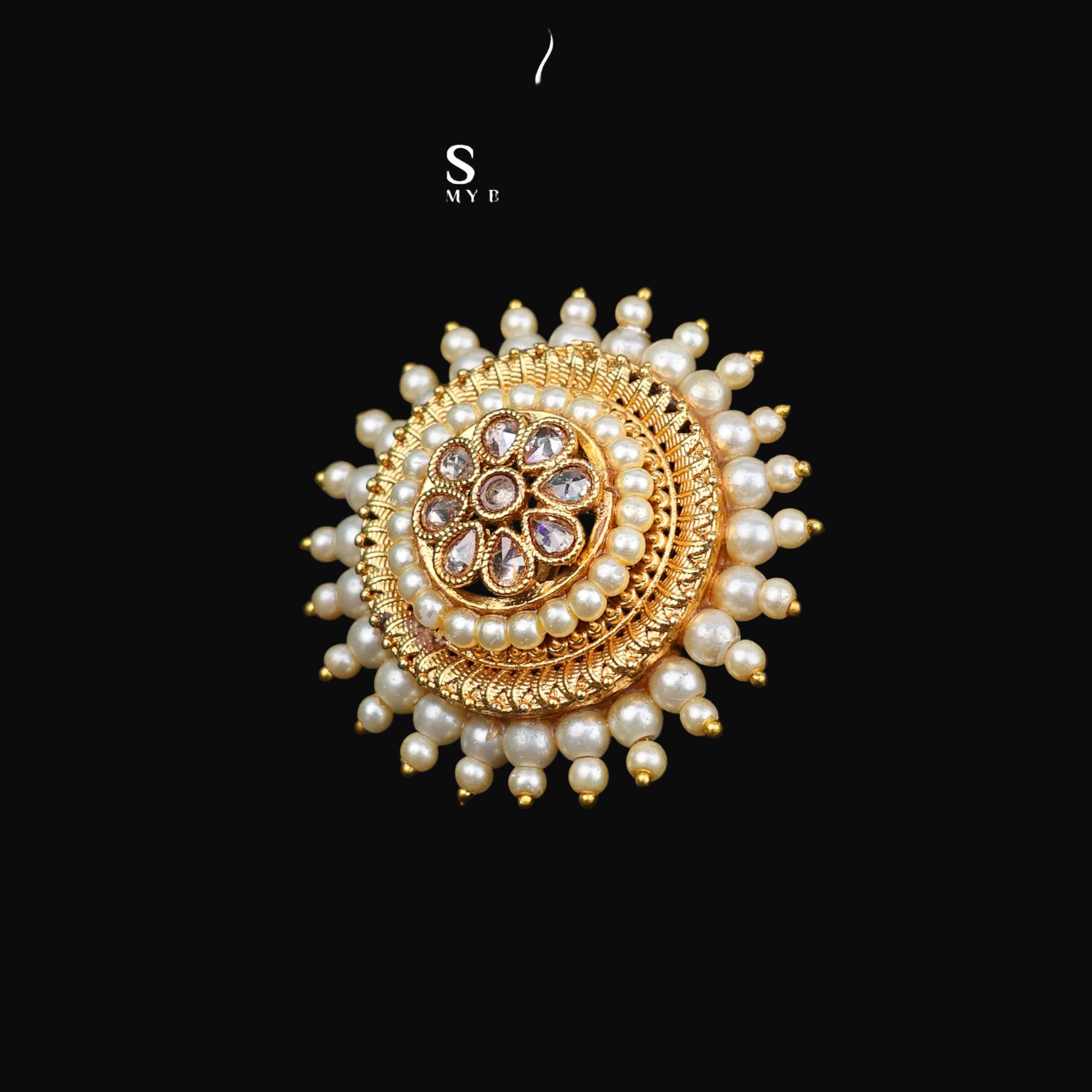 Gold and pearl brooch with 'Saheli' branding on a dark background