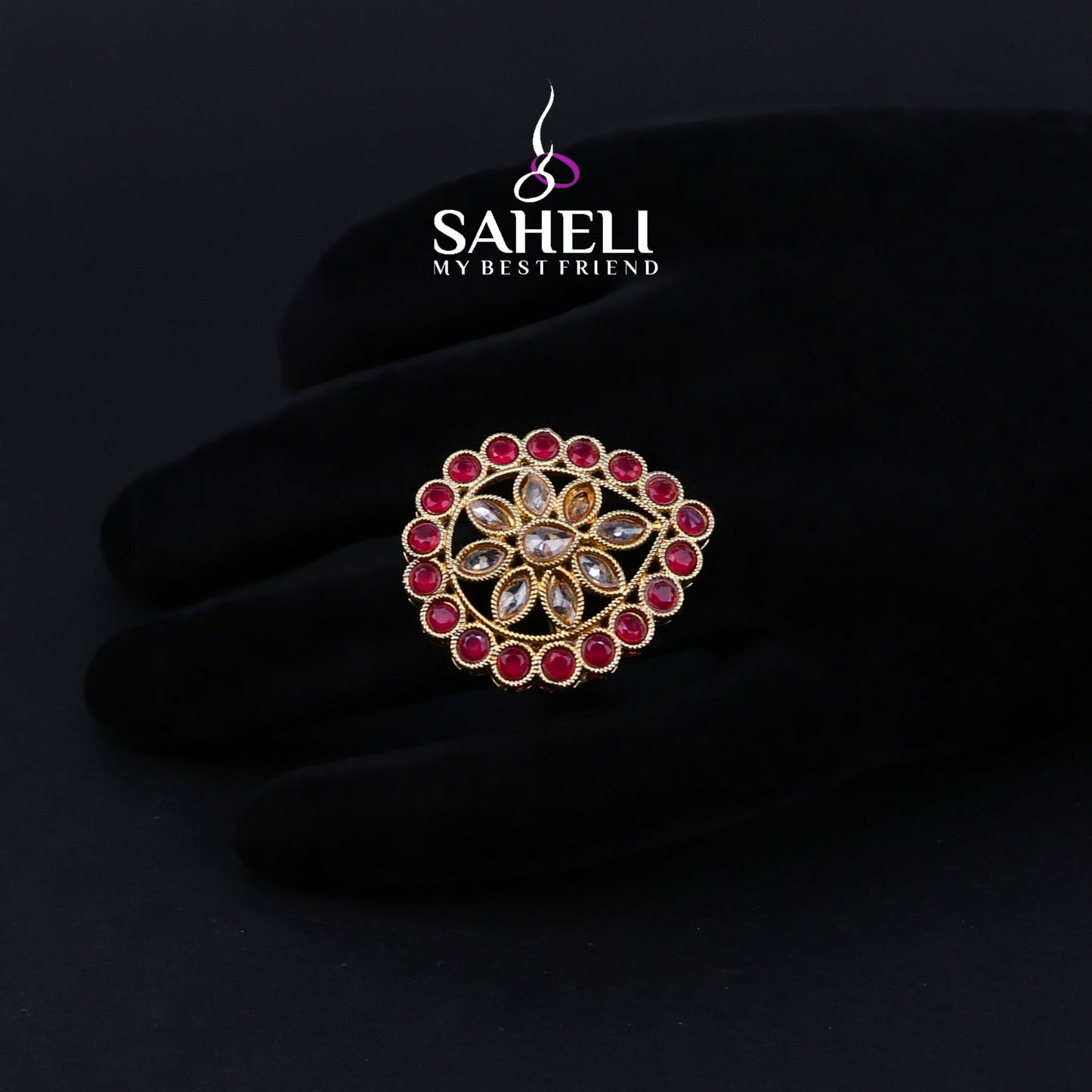 Jewelry with red gemstones on a black background, featuring the brand 'Saheli'.