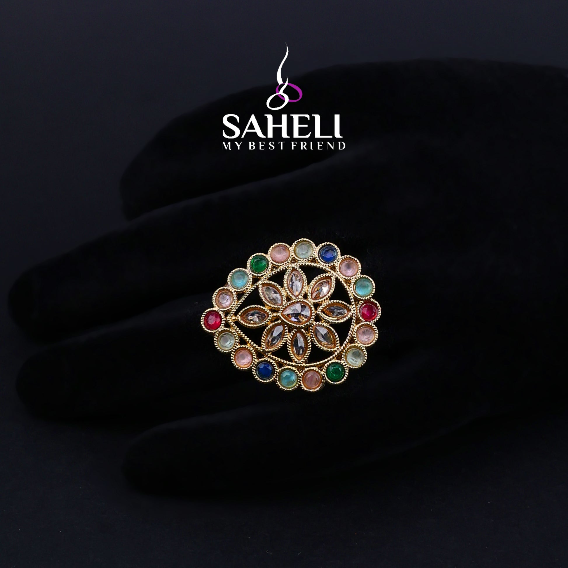 Multicolored gemstone brooch on a dark background with 'Saheli' brand logo.