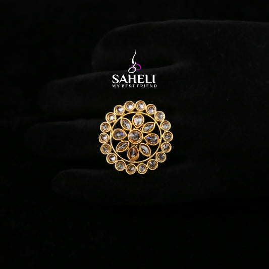 Gold brooch with gemstones on a black background, featuring the 'Saheli' brand.