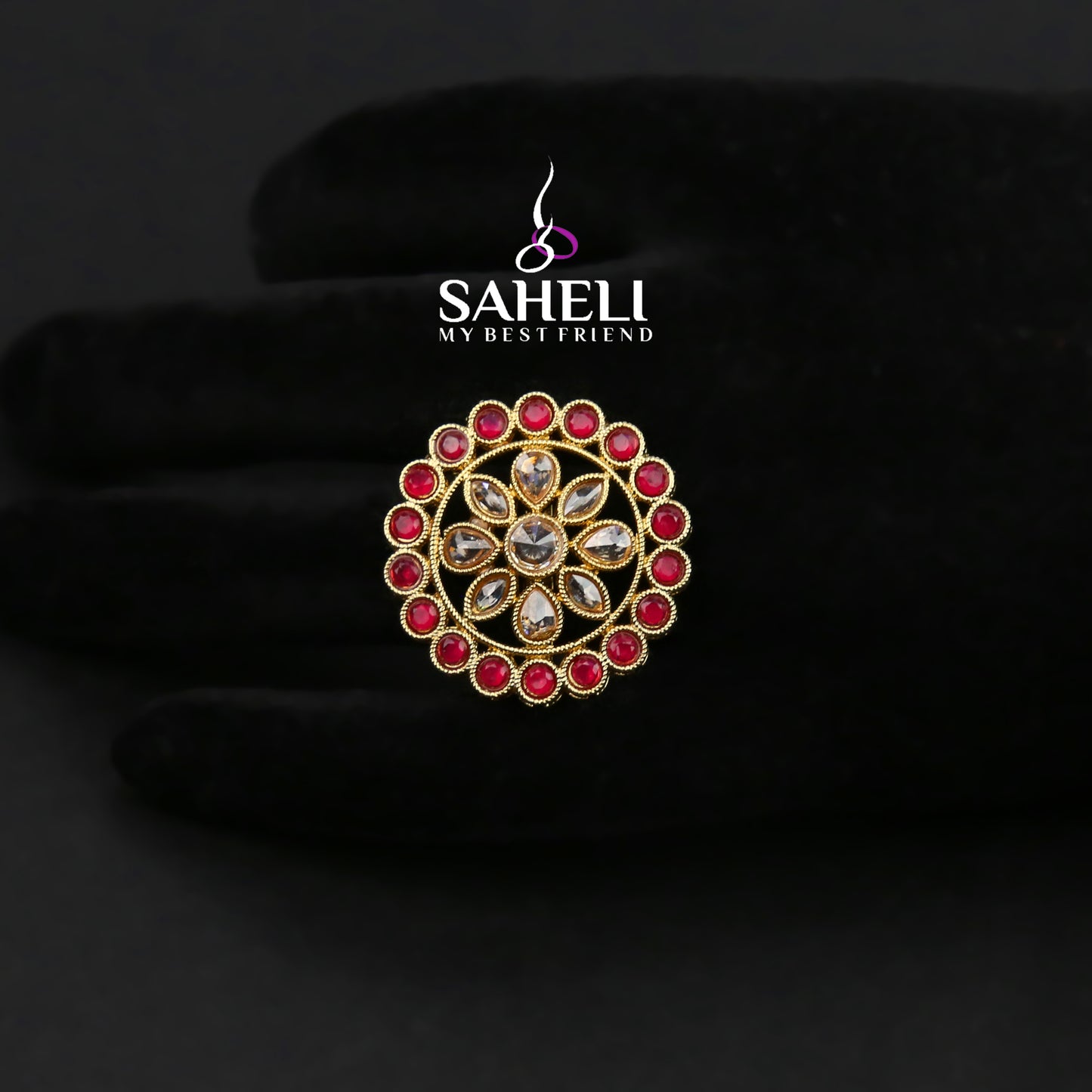 Jewelry ring with red gemstones on a black background, featuring the brand 'Saheli'.
