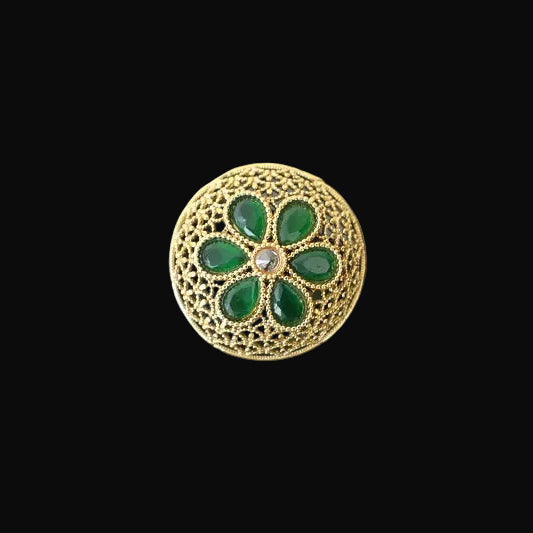 Gold ring with green gemstones on a black hand model