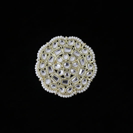 Decorative ring with gemstones on a black glove against a dark background