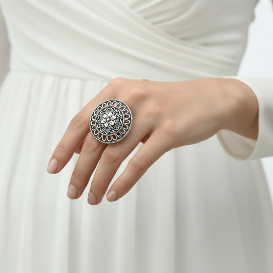 Silver ring with intricate design on a gray background