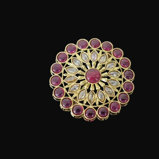 Decorative ring with gemstones on a black hand, branded 'Saheli'.