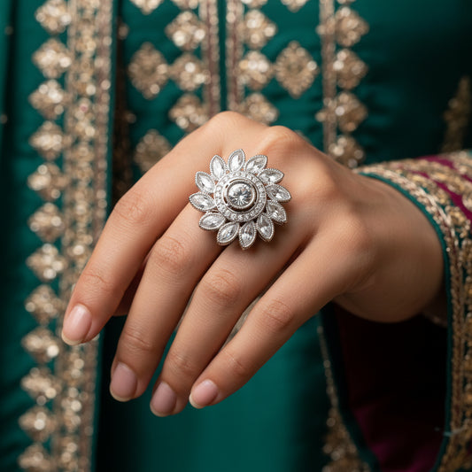 A large silver-toned floral ring with a central clear gemstone is displayed on a black velvet hand against a dark background. The brand name 'SAHELI MY BEST FRIEND' is printed in white text near the top of the hand.