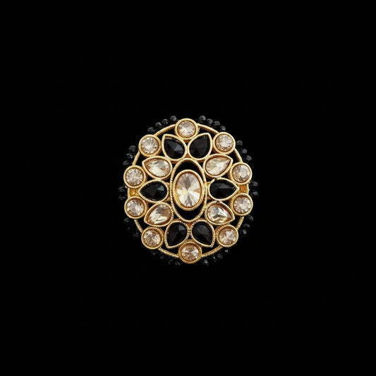 A gold-plated Kundan ring with black and clear stones, displayed on a reflective gray surface with the 'SAHELI MY BEST FRIEND' logo in the top left corner.