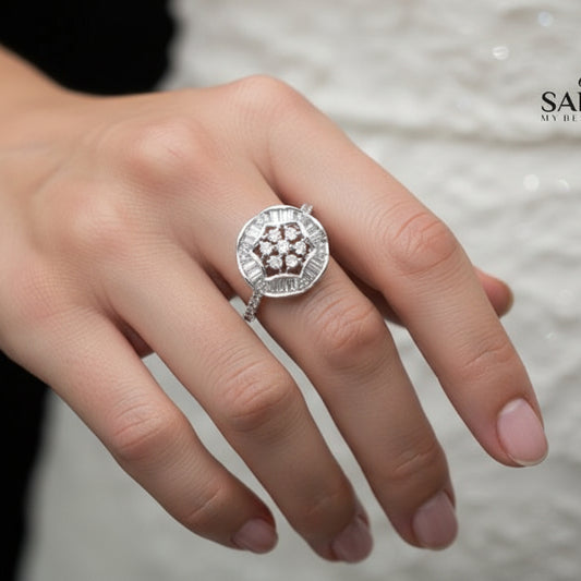 Silver ring with a diamond-like center on a black hand, branded 'Sahelli'.