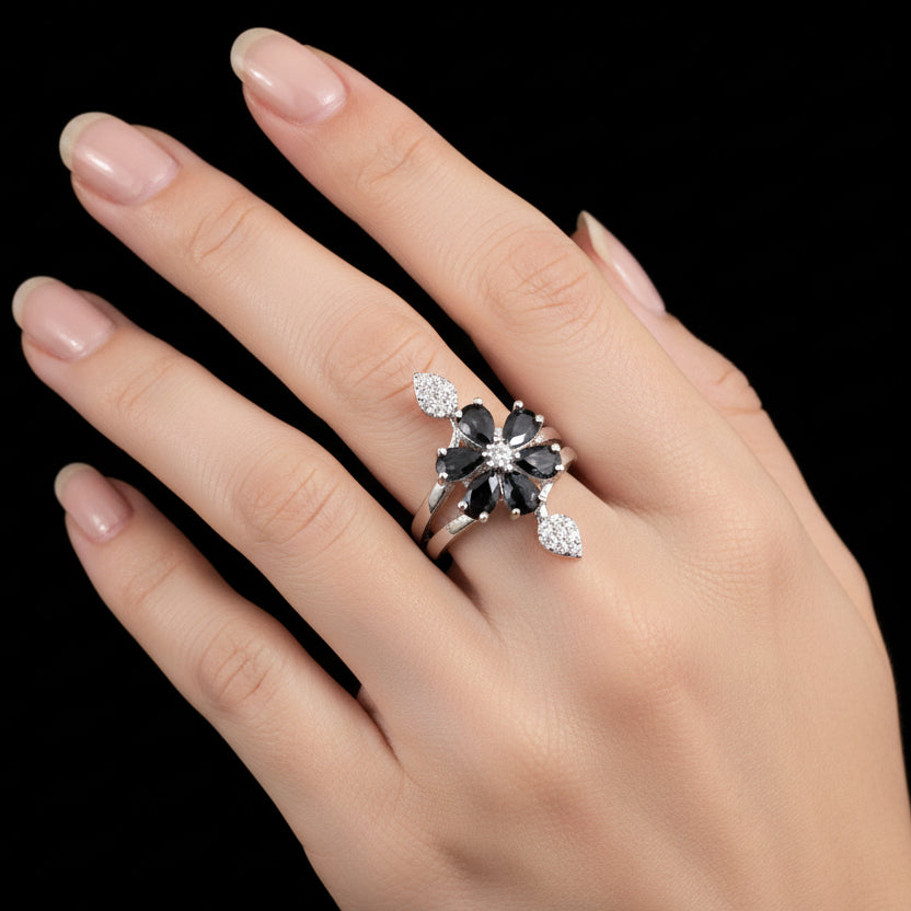 Silver ring with black gemstone on a gray background with 'SAHELI' branding.