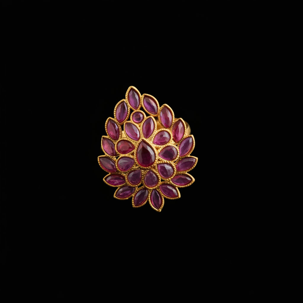 A gold-plated ring featuring a lotus-shaped floral design with deep pinkish-red inlay stones, displayed on a dark reflective surface. The Saheli Mystery Store logo is visible in the top-left corner.