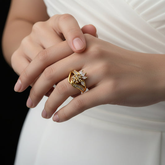 Gold ring with floral design and gemstones on a dark background