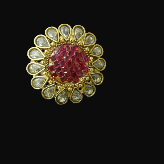 Jewelry pin with red center and gold and silver accents on a gray background, branded 'SAHELL'.