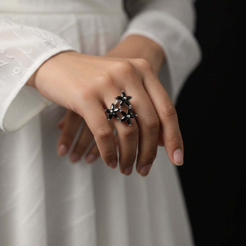 Silver ring with floral design on a gray background, featuring the brand 'Saheli'.