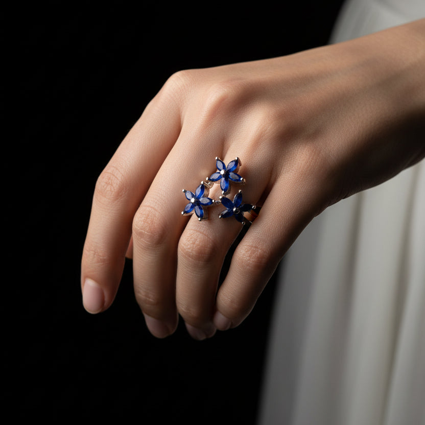Silver ring with blue gemstones on a gray background, featuring the brand 'Saheli'.