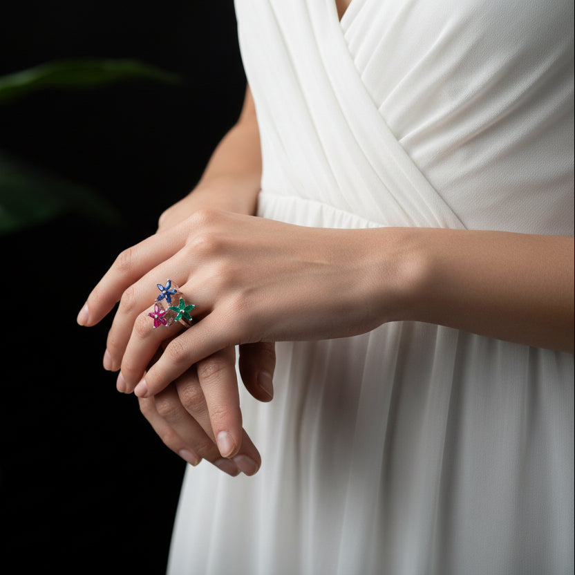 Silver ring with colorful gemstones on a gray background, featuring the brand 'Saheli'.