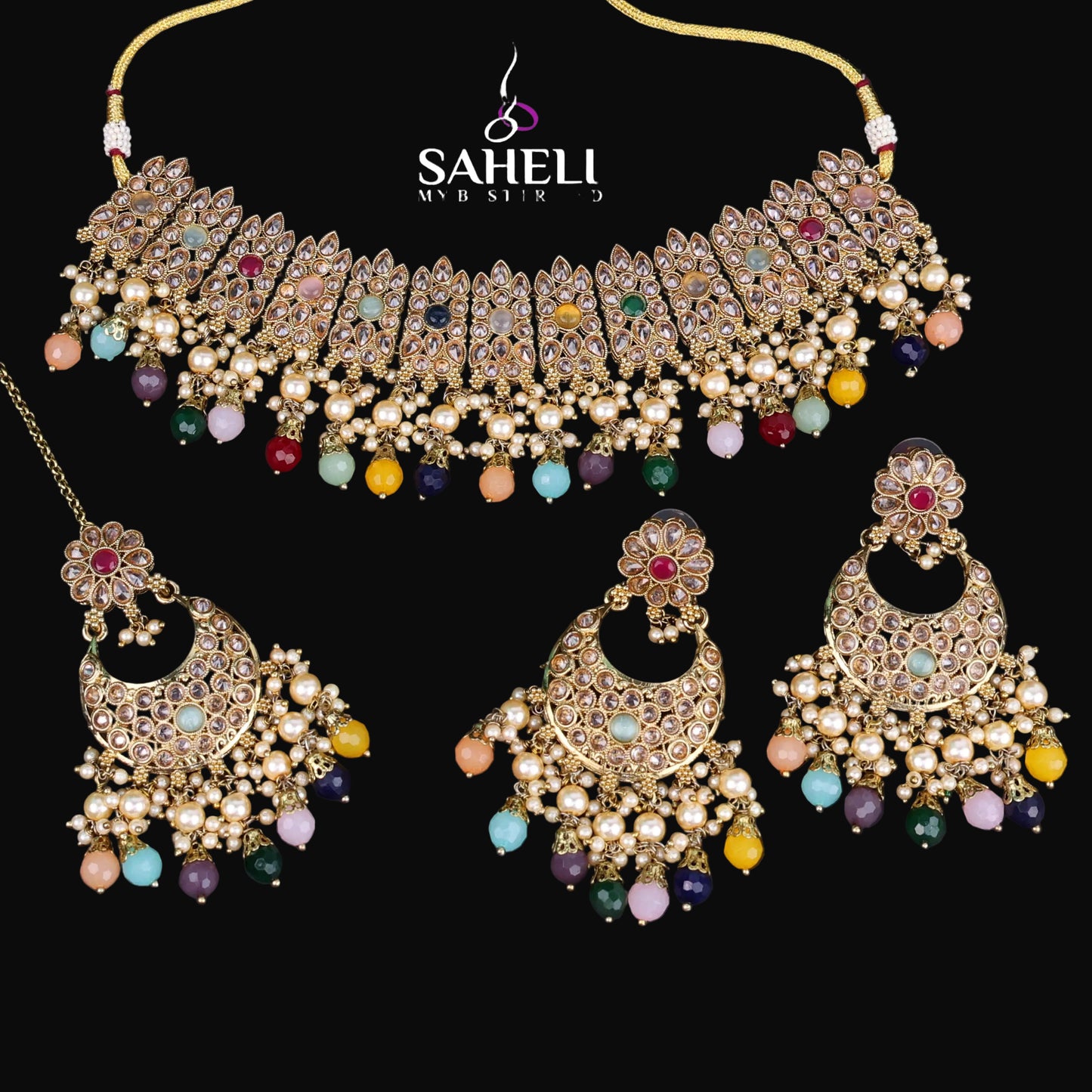Ornate jewelry set with necklace and earrings on a dark background, featuring the brand 'Saheli'.
