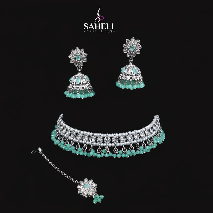 Jewelry set with choker, earrings, and necklace on a black stand with 'SAHELI' branding.