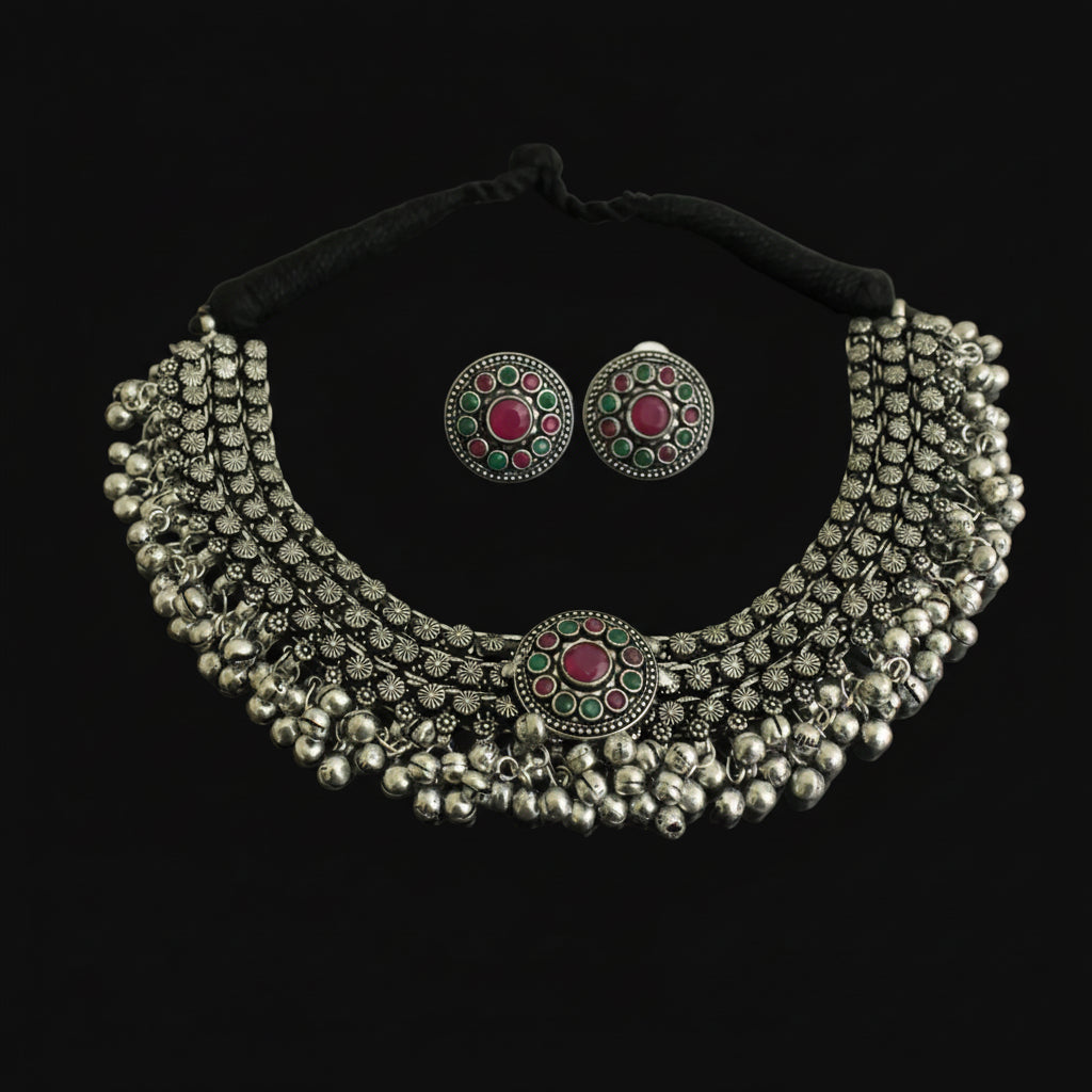 Silver necklace with red and green gemstones on a dark background