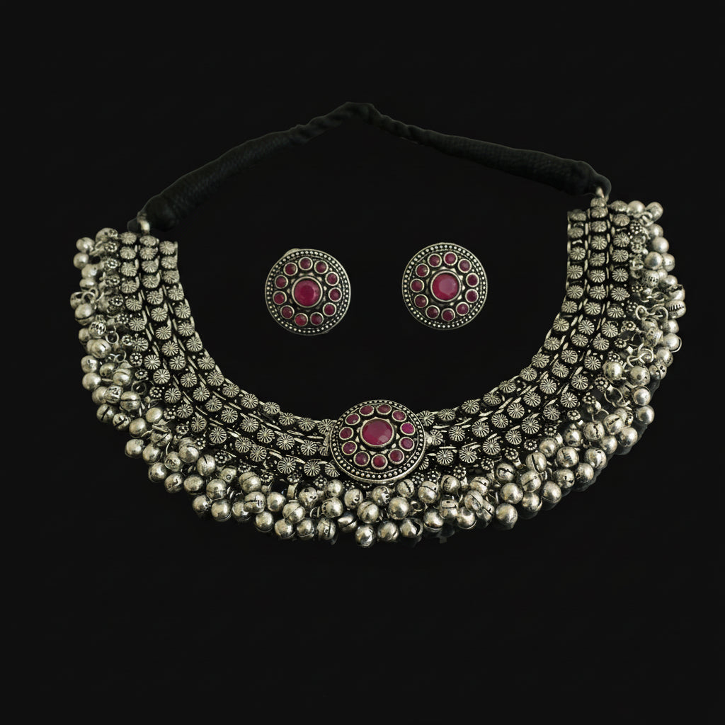 Silver necklace and earrings with red gemstones on a dark background