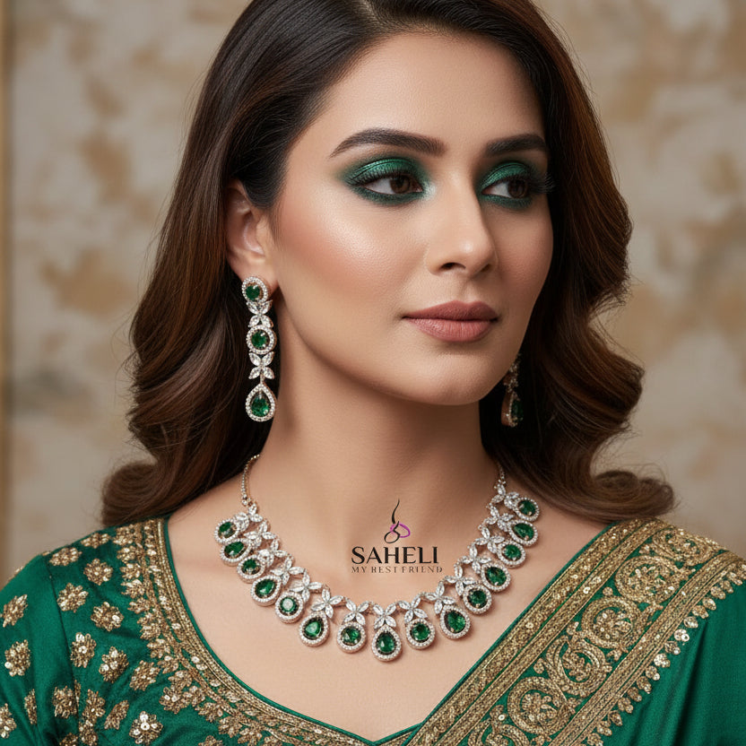 Jewelry set with necklace and earrings featuring green gemstones on a dark background, branded 'Saheli'.