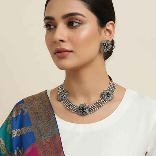 Silver necklace and earrings set on a black background