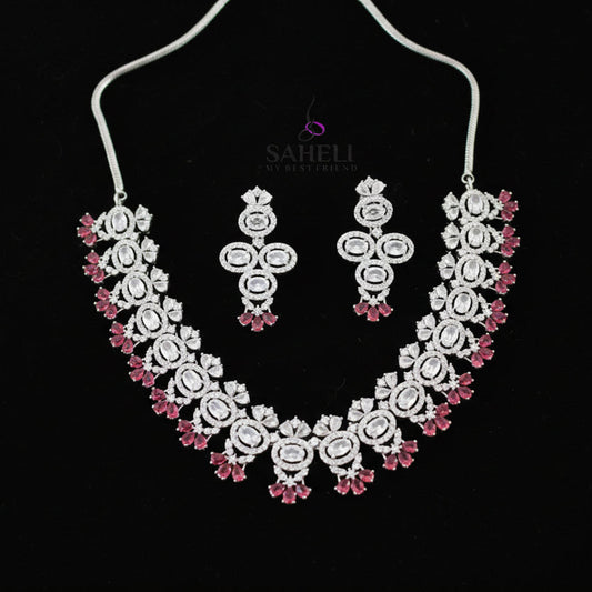 Jewelry set with necklace and earrings on a gray background, branded 'SAHELI'.