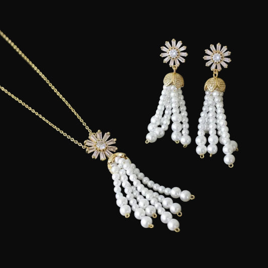 Pearl necklace and earrings with gold accents on a dark background