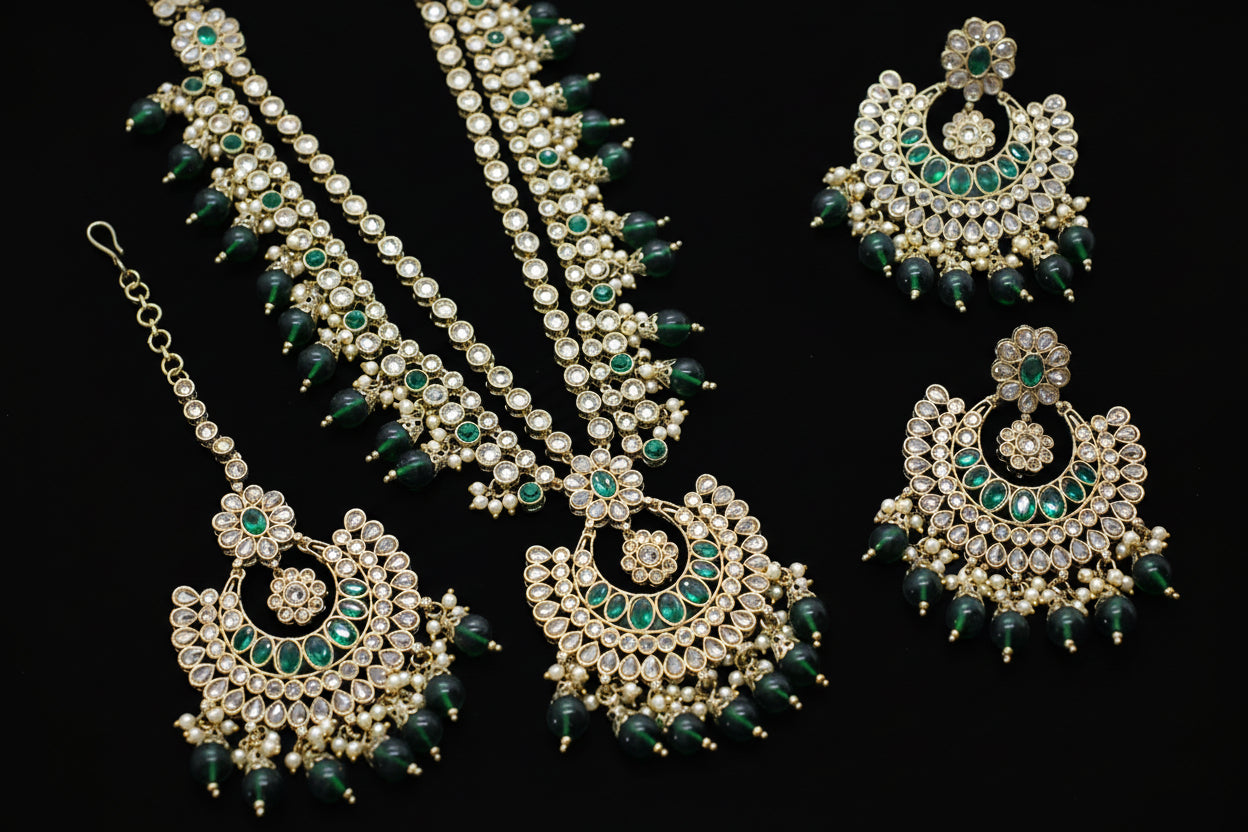 Ornate jewelry set with green and gold elements on a dark background
