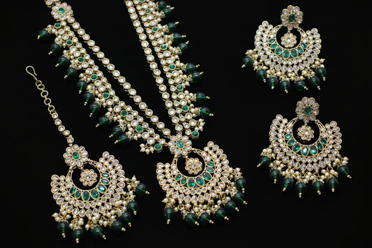 Ornate jewelry set with green and gold elements on a dark background