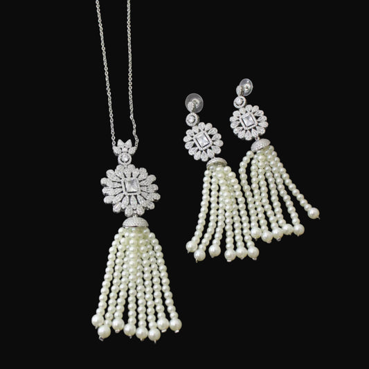 Pearl tassel necklace and earrings on a reflective surface