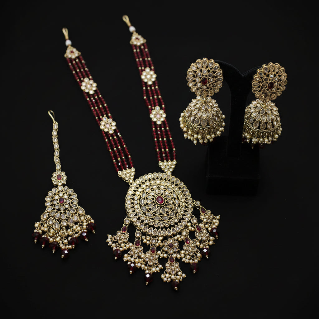 Gold and red beaded necklace with matching earrings on a dark background