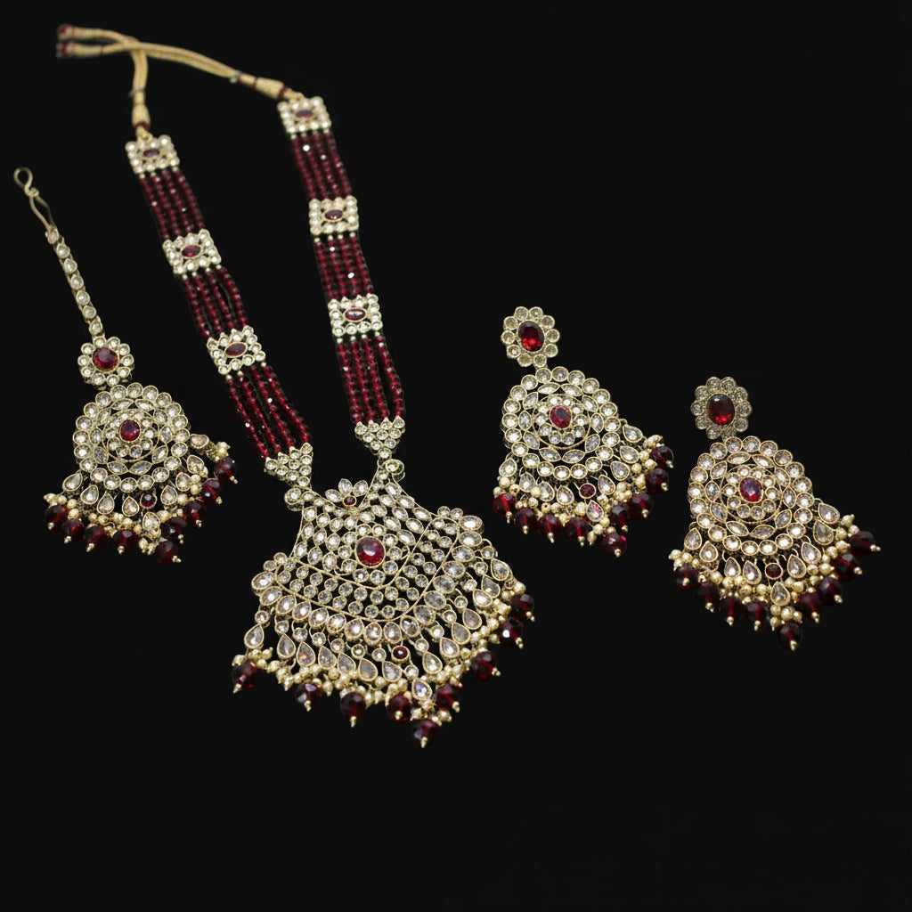Ornate necklace and earrings with red gemstones on a dark background