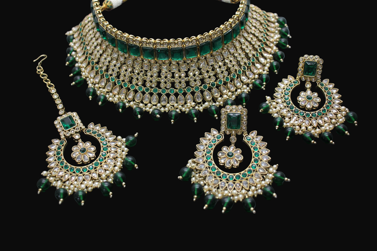 Ornate jewelry set with green and gold accents on a dark background