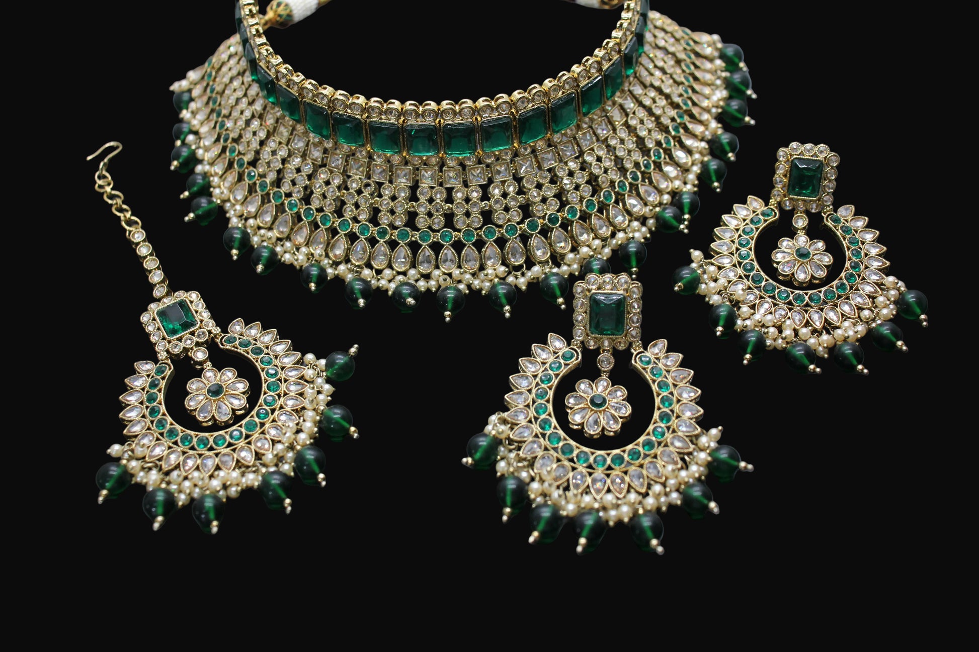 Ornate jewelry set with green and gold accents on a dark background