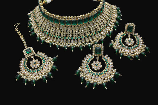 Ornate jewelry set with green and gold accents on a dark background