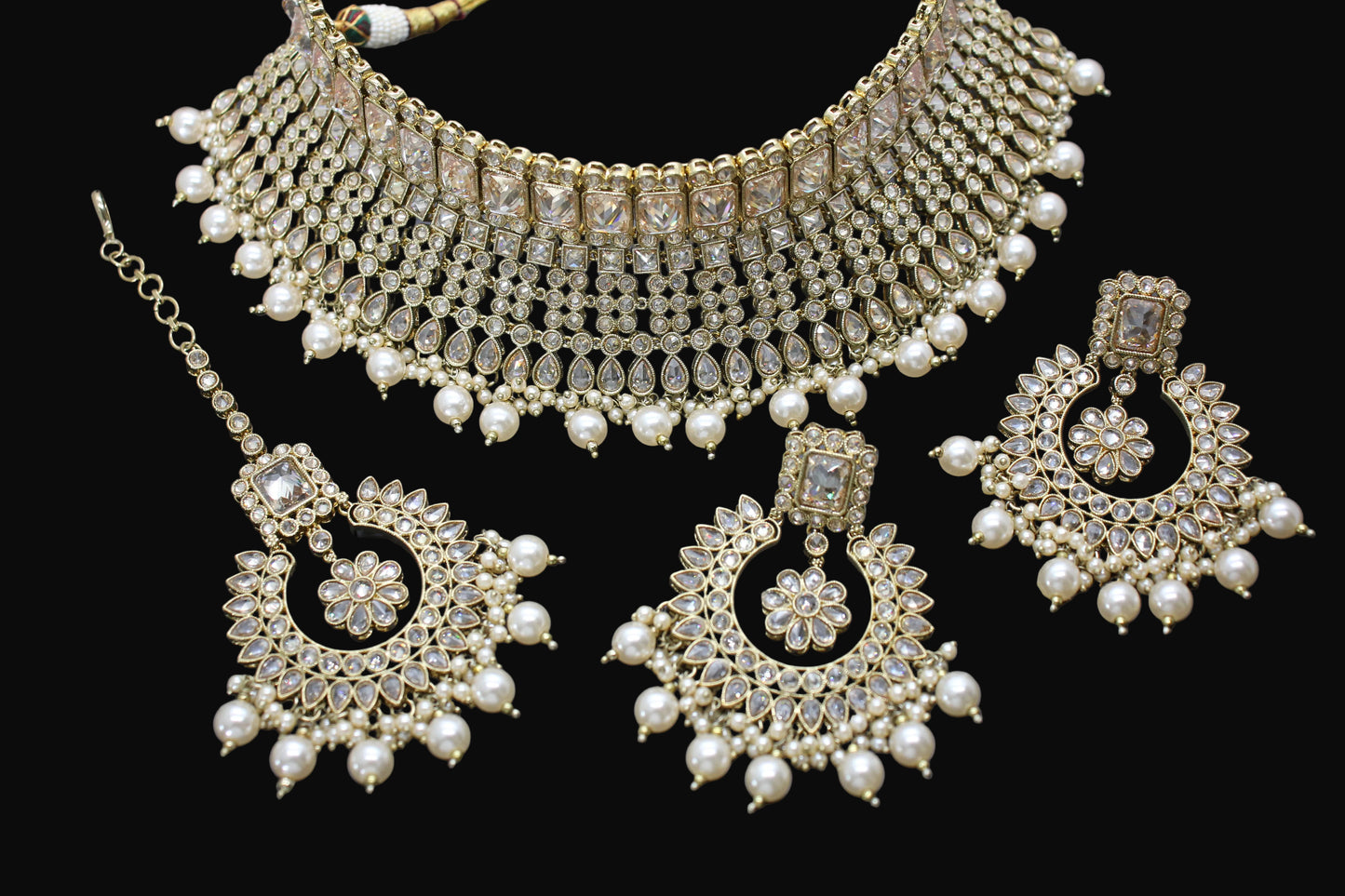 Ornate jewelry set with necklace, earrings, and choker on a dark background