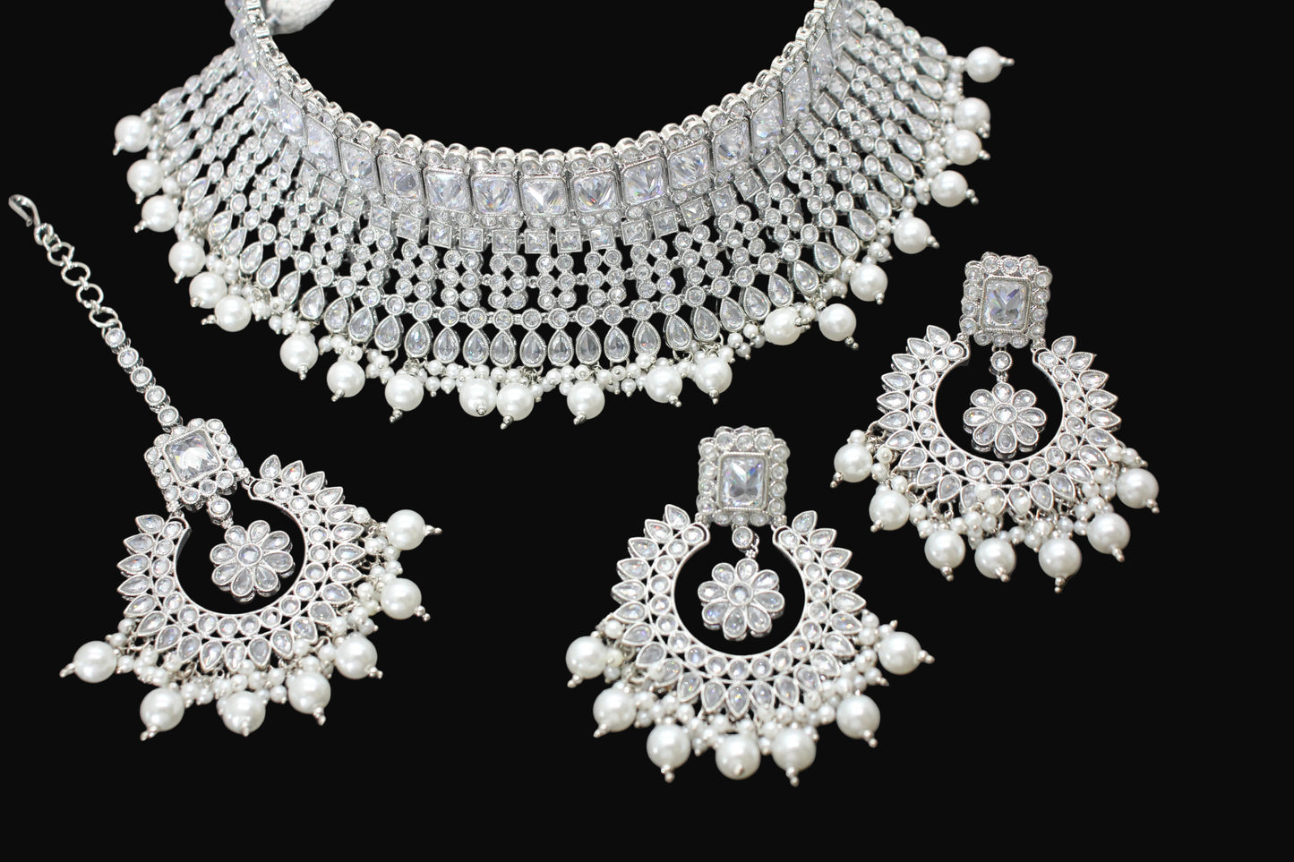 Silver jewelry set with necklace, earrings, and hair accessories on a dark background