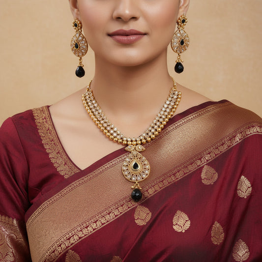 Gold necklace with black beads on a patterned surface