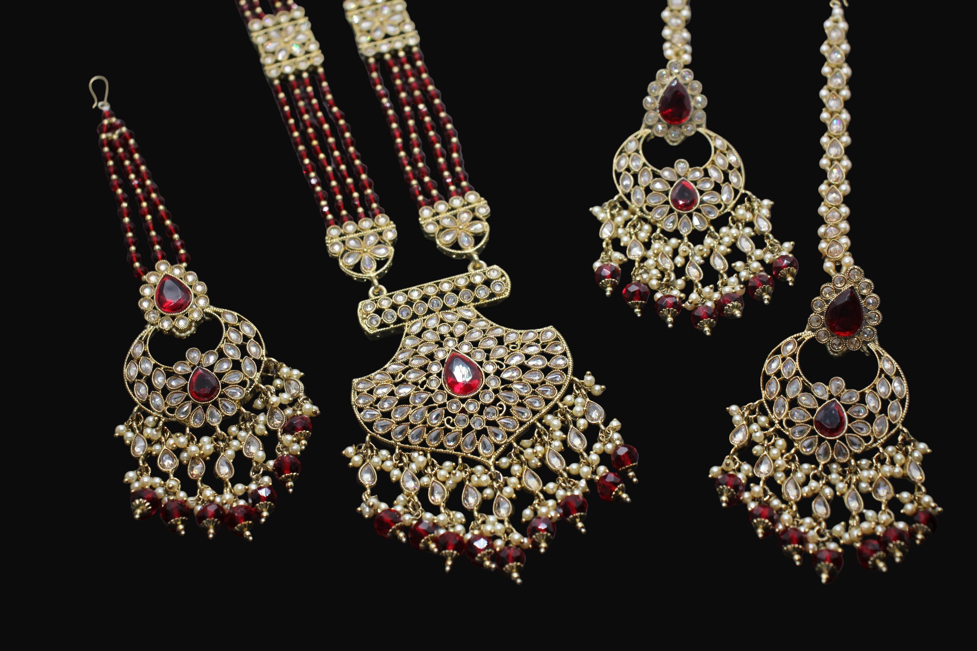 Ornate gold and red gemstone jewelry set on a dark background