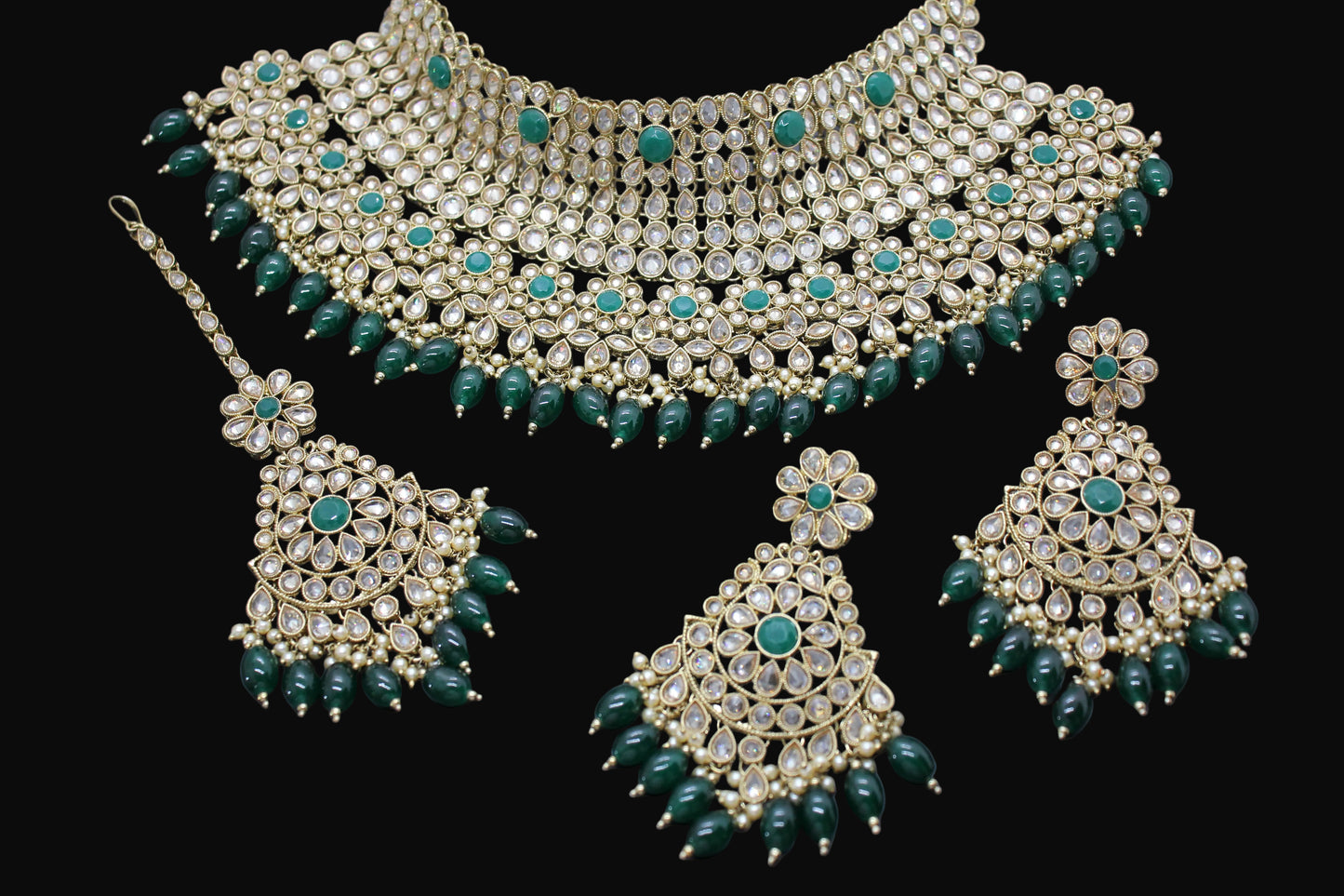 Green and gold jewelry set on a dark background